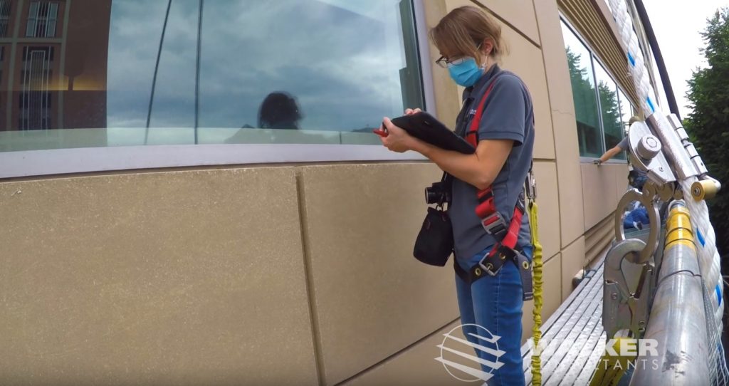 Restoration Consultant Erika Green makes notes on an iPad as she examines a building facade from a swing stage