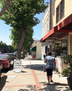 Streetscape in downtown Benicia with pedestrian, shops, and parked cars