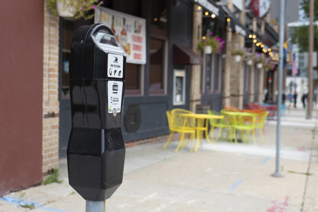 A parking meter for a curb space with sidewalk dining in the background