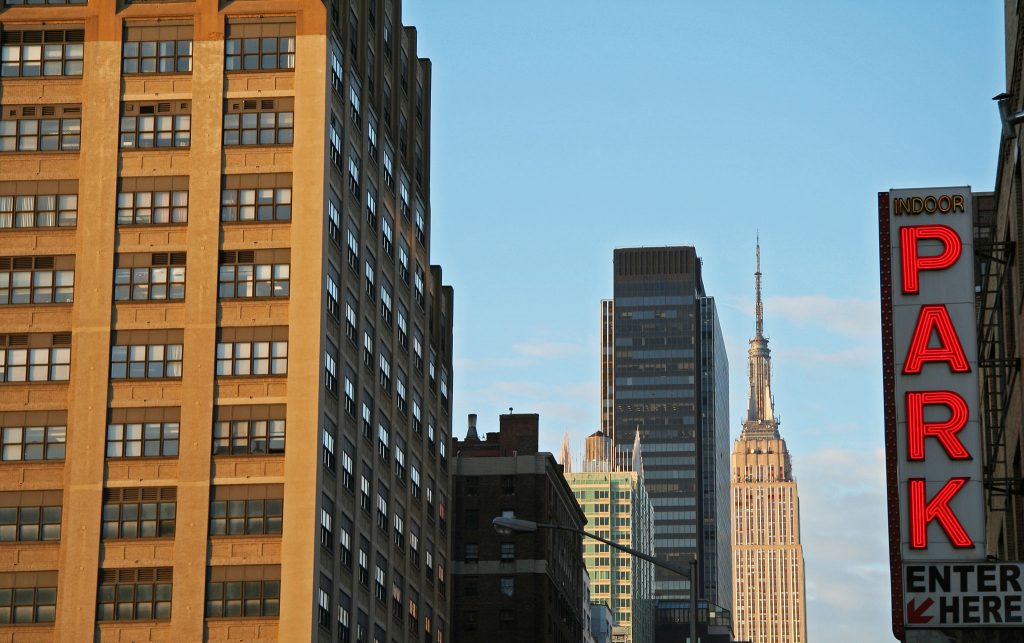 New York City skyline with Empire State Building and neon "PARK" sign in foreground