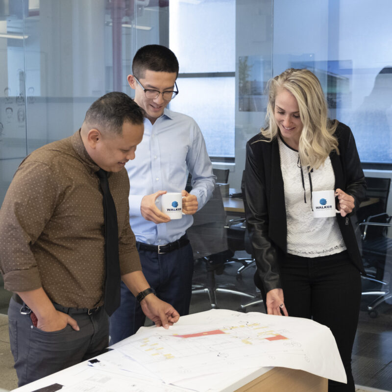 Three colleagues look at a set of drawings together in a Walker office